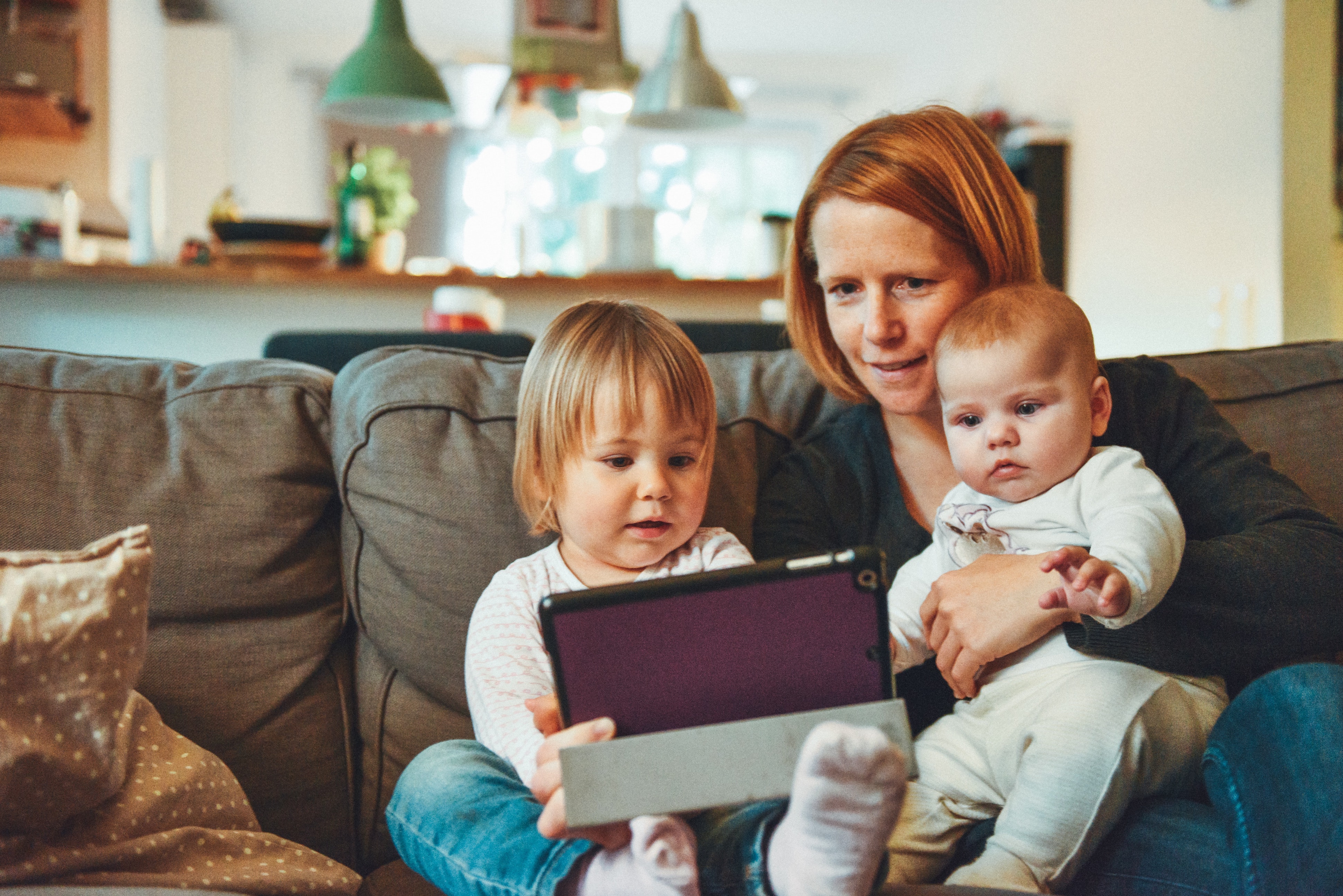 Mother with two toddlers holding a tablet